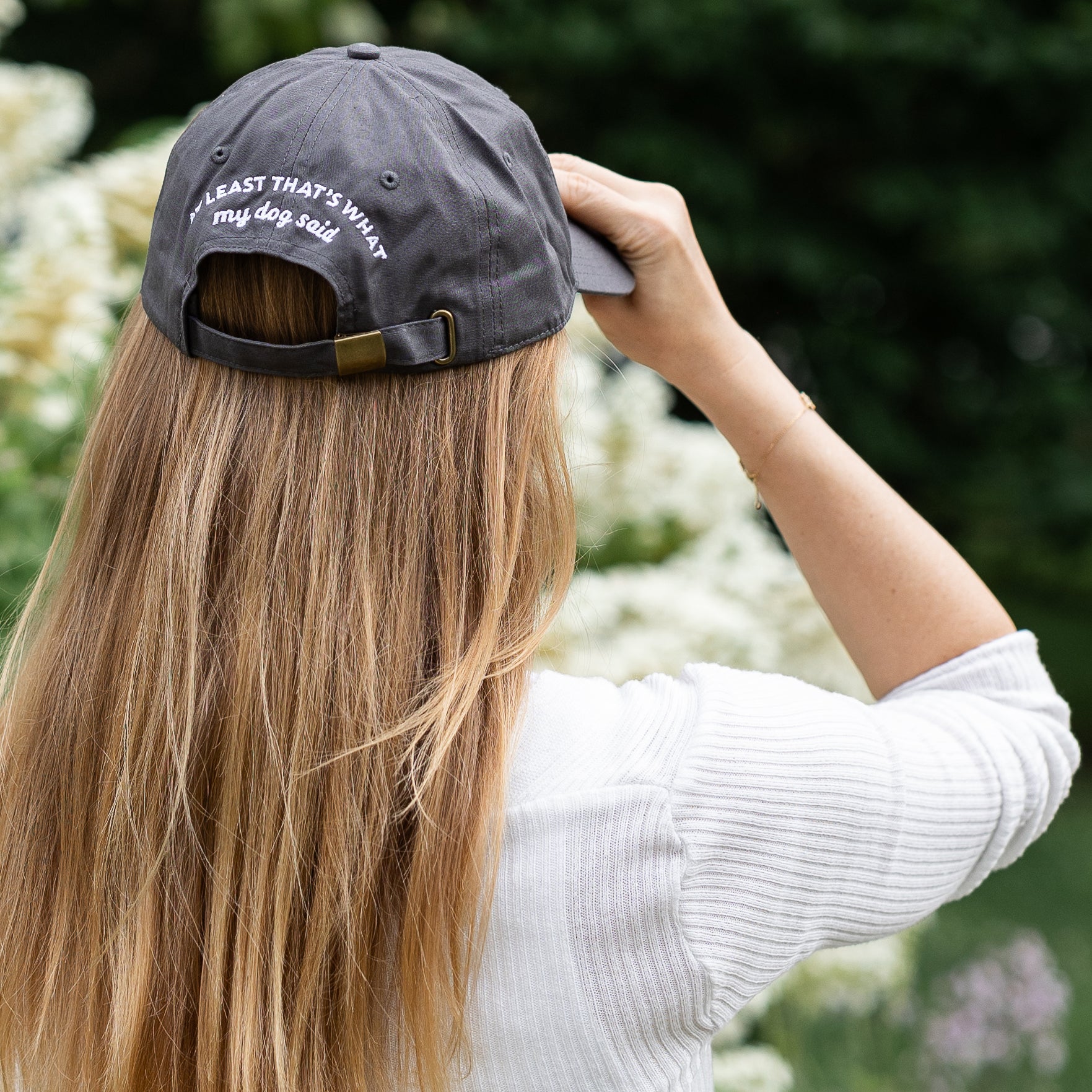 Female model wearing grey embroidered hat that says "Good Human, at least that's what my dog said."